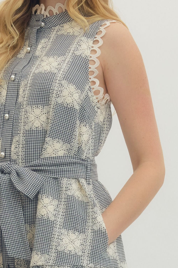 Woman wearing a blue and white checkered dress with lace details on a plain background
