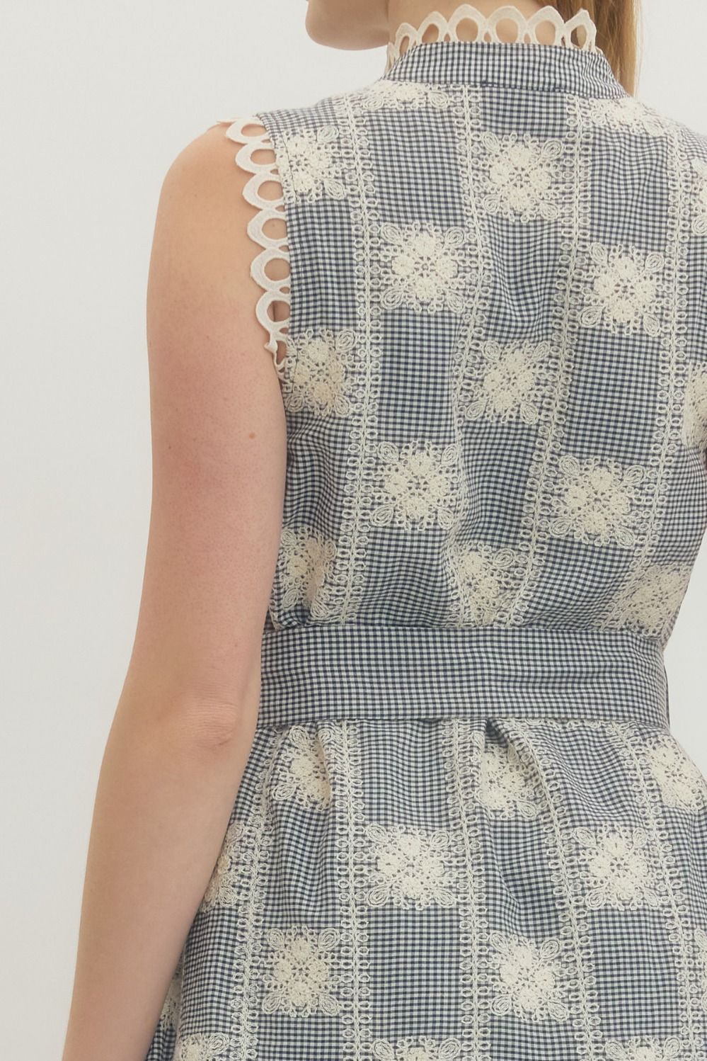 Sleeveless dress with floral pattern and lace details on a plain background