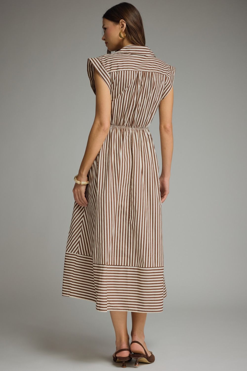 Woman wearing a striped dress against a gray background
