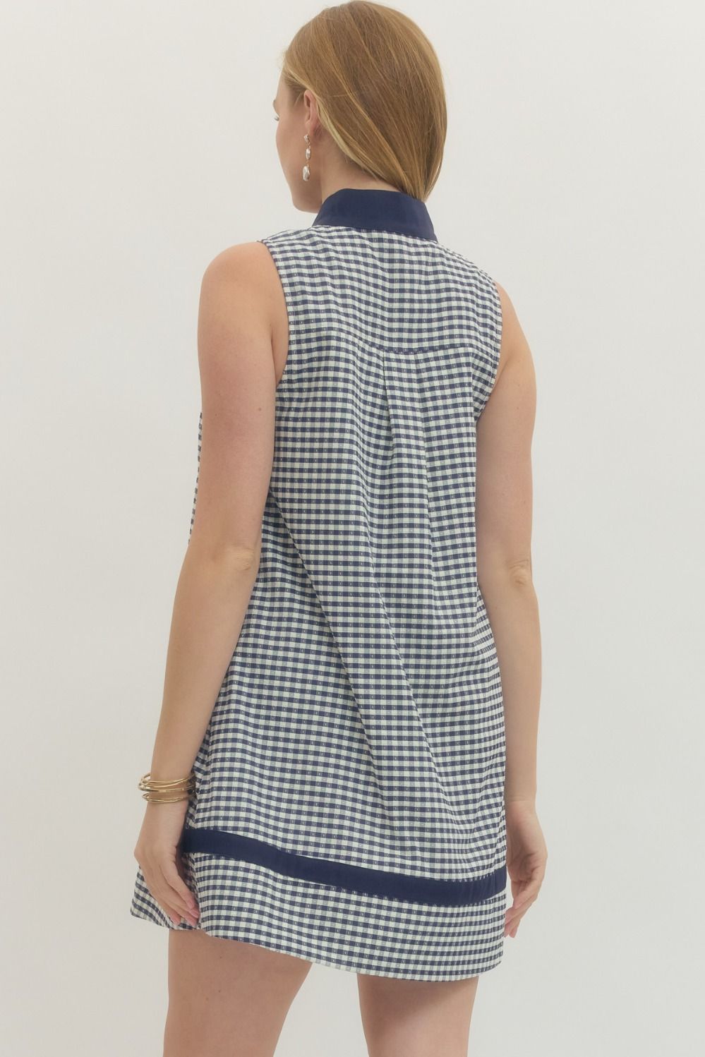 Woman wearing a checkered dress with navy trim on a plain background