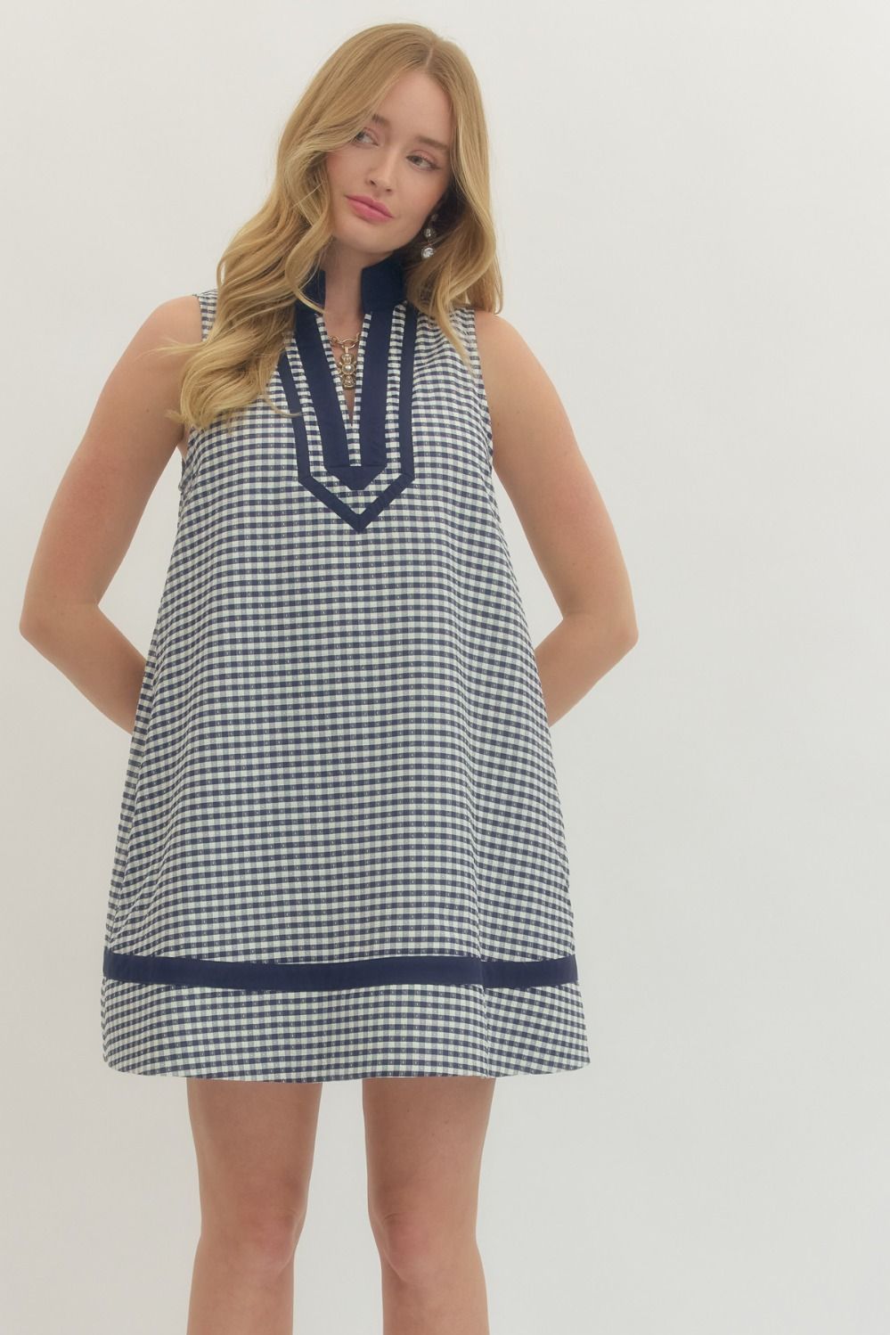Woman wearing a checkered dress with navy trim on a white background