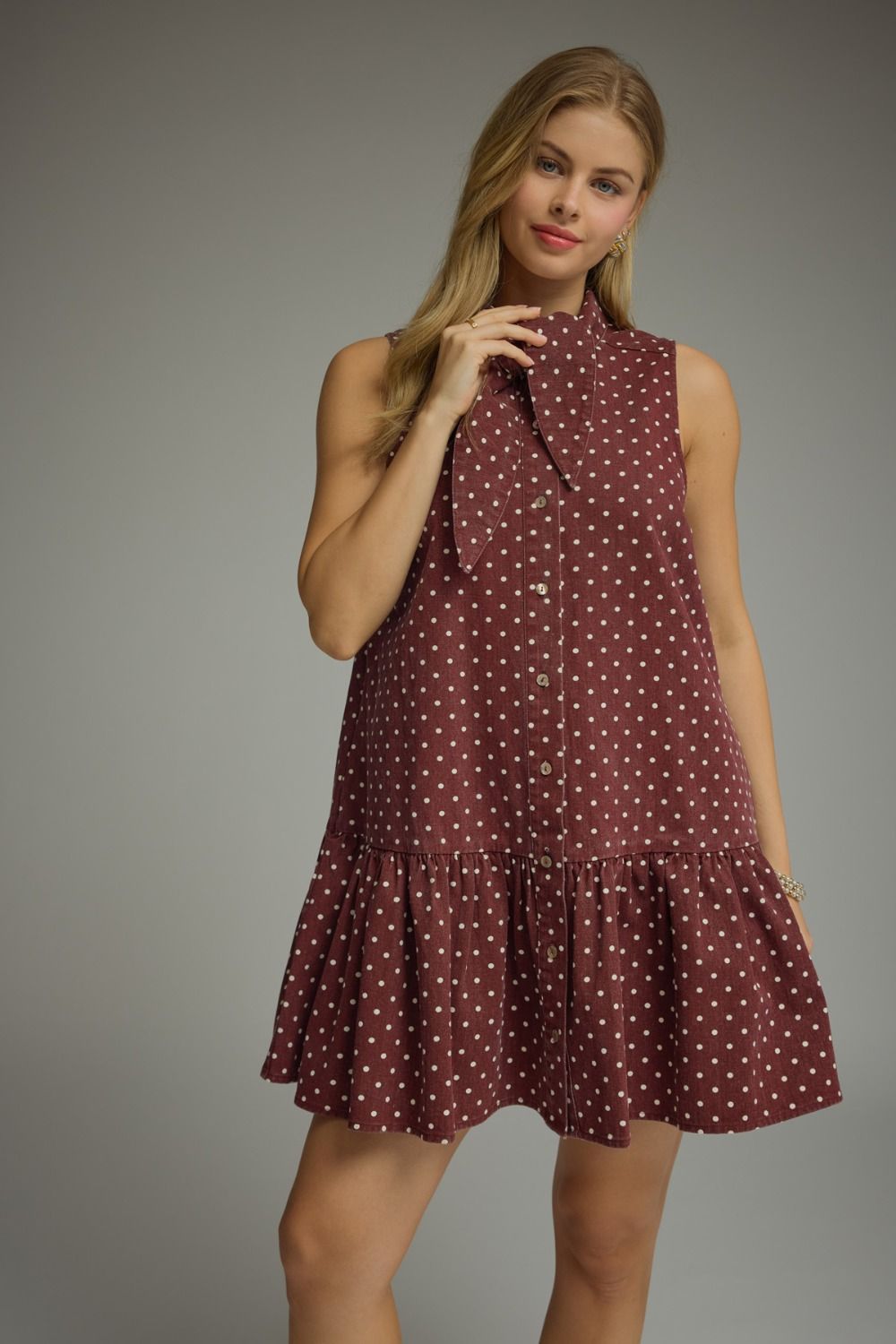 Woman wearing a sleeveless dress with a polka dot pattern on a gray background