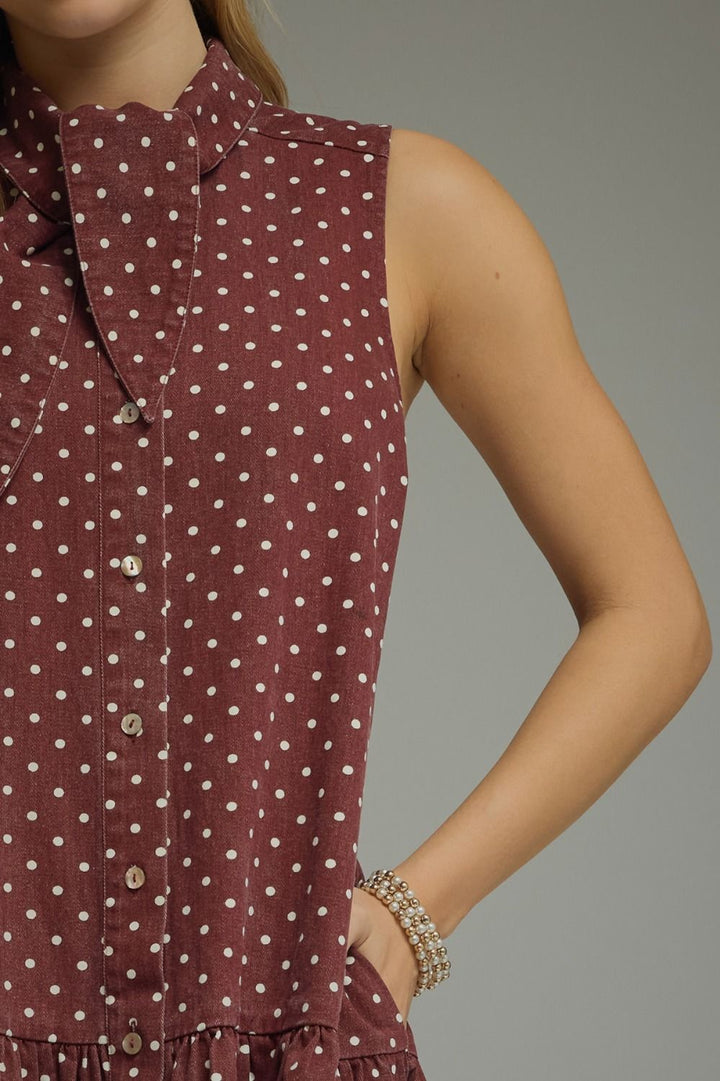 Close-up of a maroon dress with white polka dots on a gray background