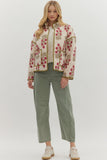 Woman wearing a floral embroidered jacket and green pants on a white background
