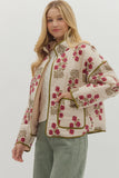 Woman wearing a floral quilted jacket on a plain background