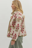 Woman wearing a floral embroidered jacket on a plain background
