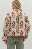 Woman wearing a floral quilted jacket on a plain background