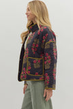 Woman wearing a floral embroidered jacket on a plain background