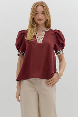 Woman wearing a burgundy blouse with lace details on a white background