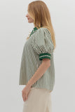 Woman wearing a green and white striped shirt with a plain background