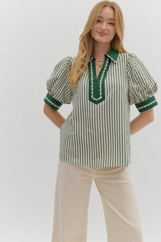 Woman wearing a green and white striped blouse with a plain background