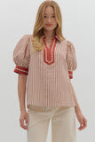 Woman wearing a red and white striped blouse with puff sleeves on a plain background