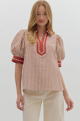 Woman wearing a red and white striped blouse with puff sleeves on a plain background