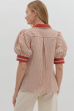 Woman wearing a red and white striped shirt with puffed sleeves on a plain background
