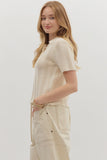 Woman wearing a beige knitted top and pants on a white background