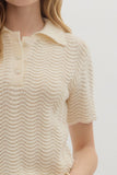 Close-up of a person wearing a textured beige short-sleeve top against a white background