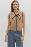 Woman wearing a beige knitted vest with a collar against a plain background