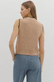 Woman wearing a beige knitted vest and blue striped pants on a light gray background