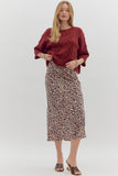 Woman wearing a red sweater and leopard print skirt on a white background