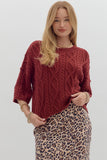Woman wearing a red cable knit sweater and leopard print skirt on a white background