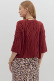 Person wearing a red cable knit sweater and leopard print skirt on a plain background