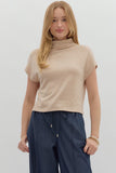 Woman wearing a beige sleeveless top and navy pants on a white background