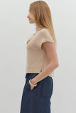 Woman wearing a beige sleeveless top and navy pants against a white background