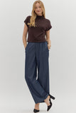 Woman wearing a brown top and blue pants on a white background