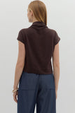 Woman wearing a brown turtleneck top and blue pants on a white background