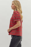 Woman wearing a red plaid shirt and black pants on a light gray background