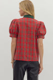 Person wearing a red plaid shirt with puff sleeves on a plain background