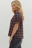 Woman wearing a plaid shirt and black pants on a plain background