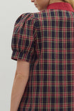 Person wearing a red and blue plaid dress with puffed sleeves on a white background