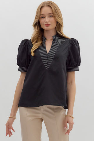 Woman wearing a black blouse with puff sleeves against a white background
