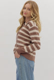 Woman wearing a brown and beige striped sweater with blue jeans on a white background