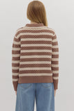 Person wearing a brown and beige striped sweater with blue jeans on a white background