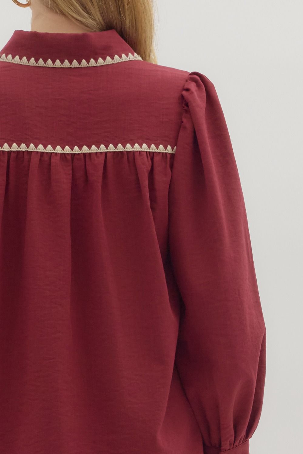 Red blouse with decorative trim on a plain background