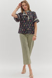 Woman wearing a floral blouse and green pants on a white background