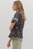 Woman wearing a floral blouse with rolled-up sleeves on a plain background