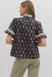 Woman wearing a floral blouse with ruffled sleeves on a plain background