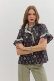 Woman wearing a floral blouse with ruffled sleeves on a plain background
