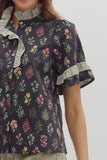 Floral patterned blouse with ruffled collar on a plain background
