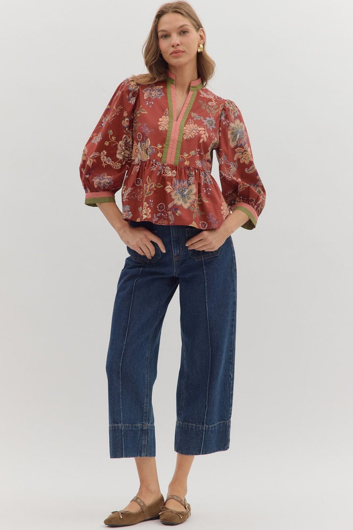 Woman wearing a red floral blouse and blue jeans on a white background