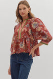 Woman wearing a red floral blouse with blue jeans on a white background
