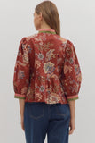 Woman wearing a red floral blouse and blue jeans on a white background