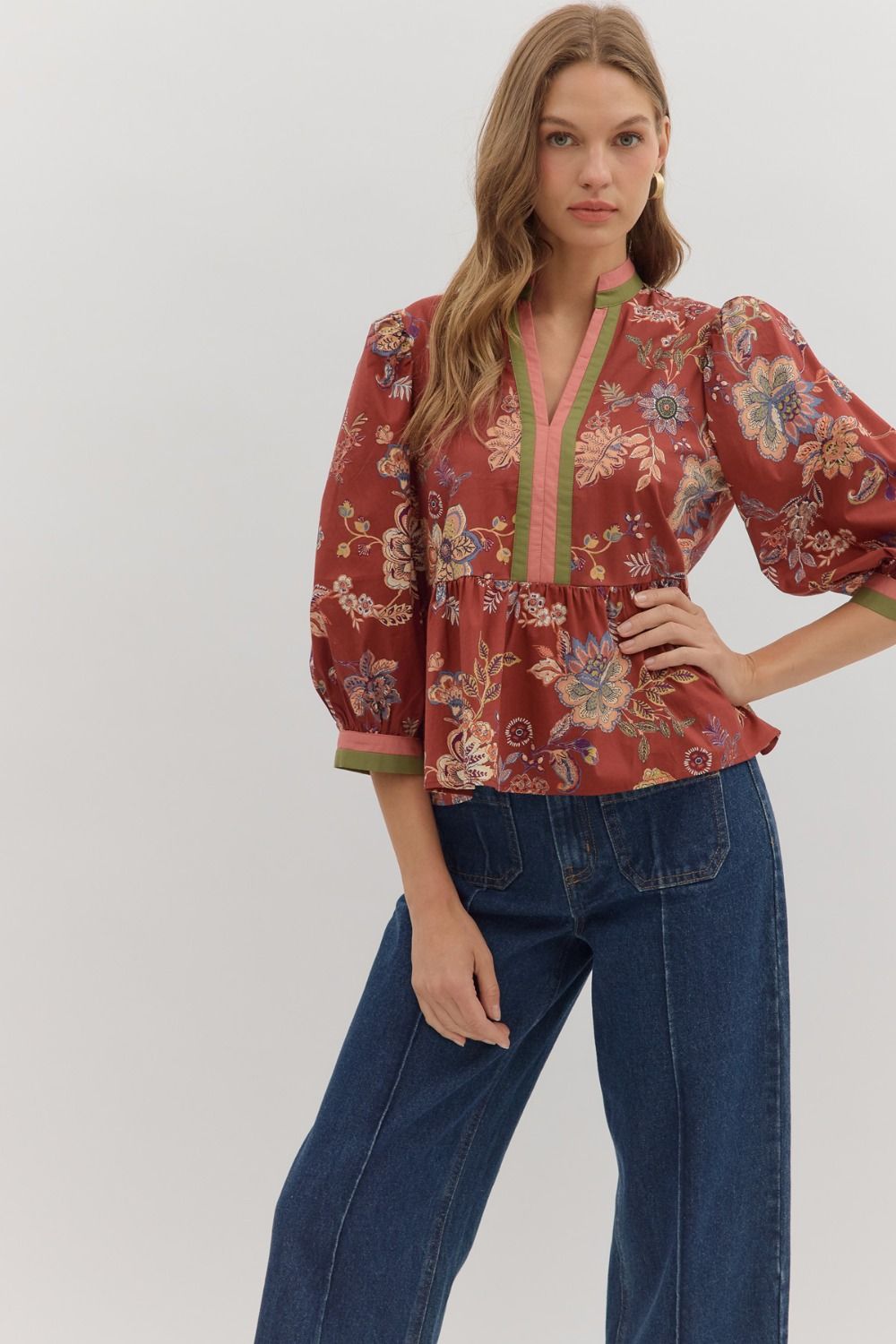 Woman wearing a floral blouse and blue jeans on a white background