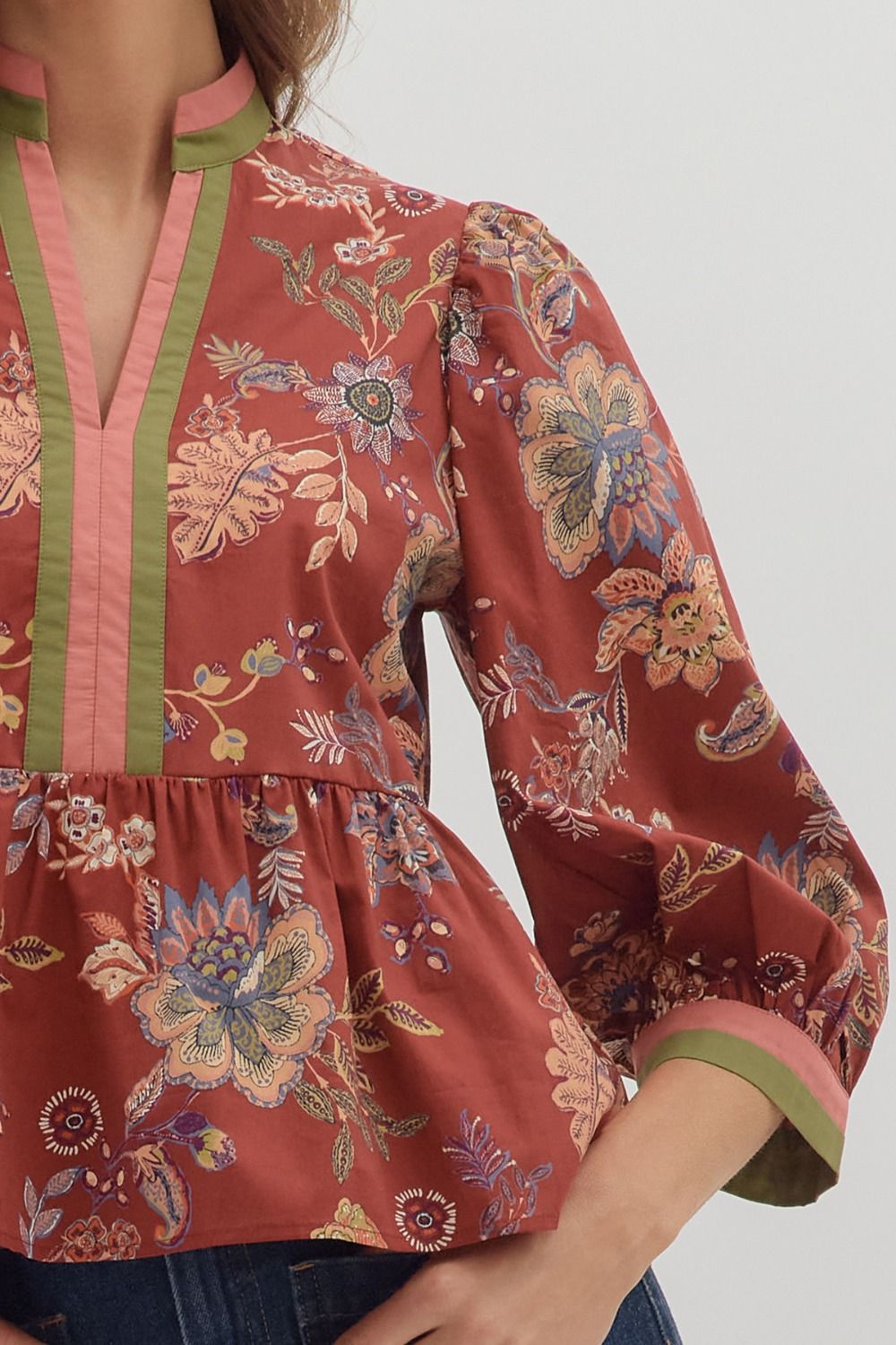 Floral patterned blouse with green accents on a plain background