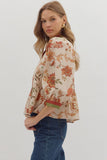 Woman wearing a floral blouse with bell sleeves on a plain background