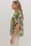 Woman wearing a green floral blouse against a white background