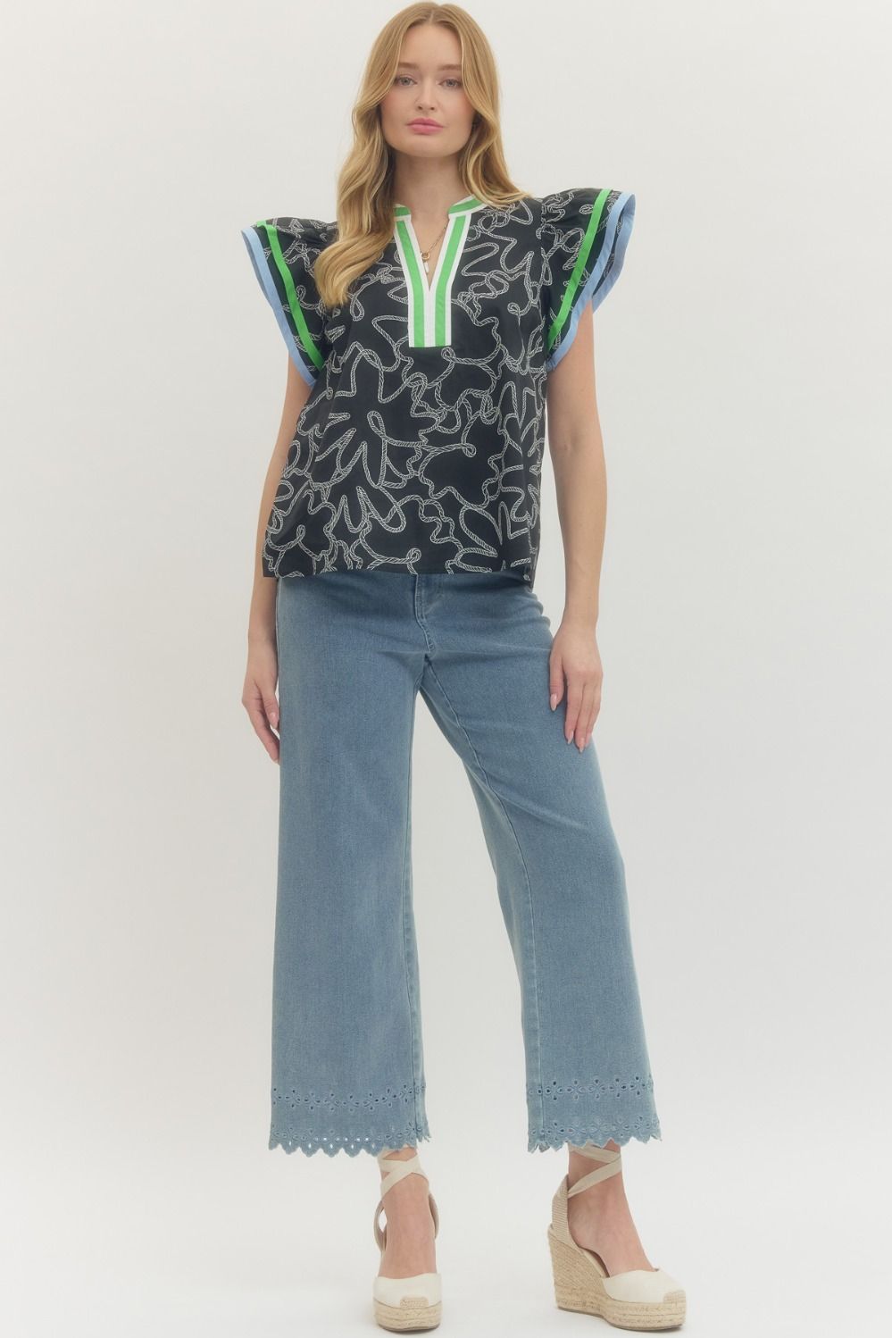 Woman wearing a patterned top and jeans on a white background